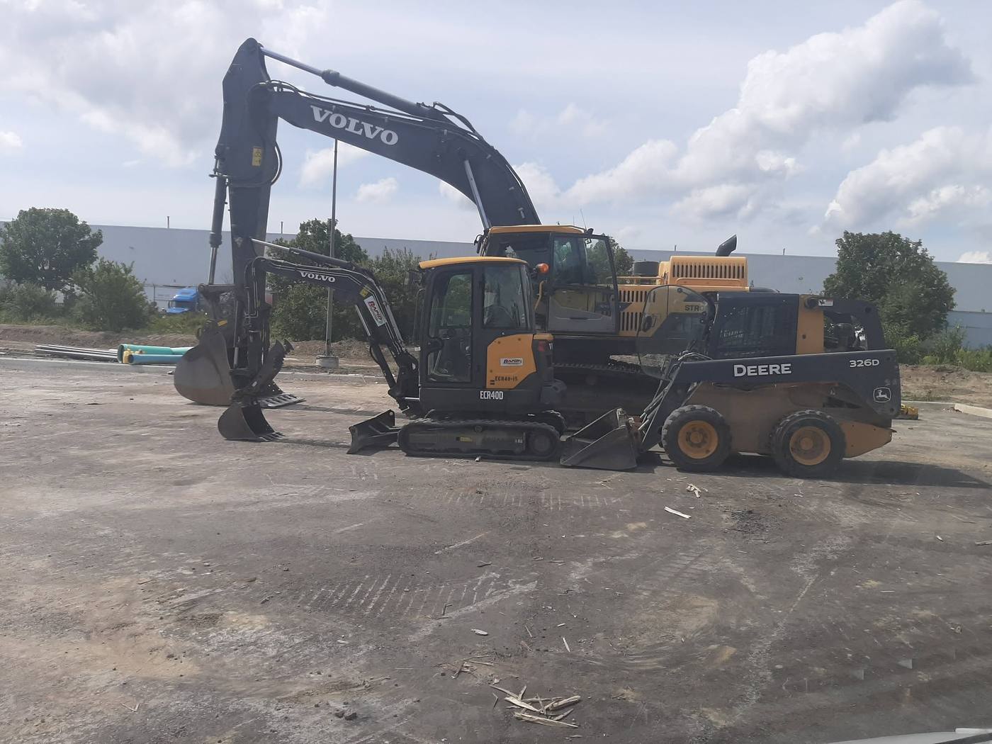 Lineup of serviced machines — Volvo excavators, a loader and a John Deere 326D skid steer on site